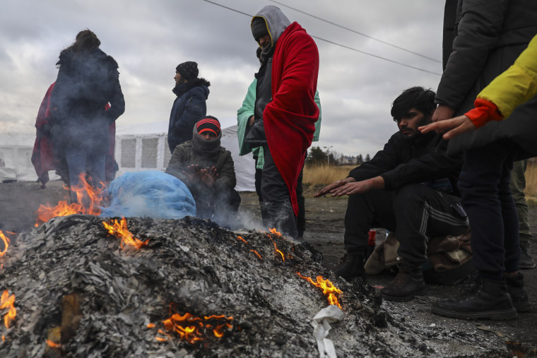 Refugiados que huyen de Ucrania sentados junto a una hoguera tras cruzar la frontera con Polonia.