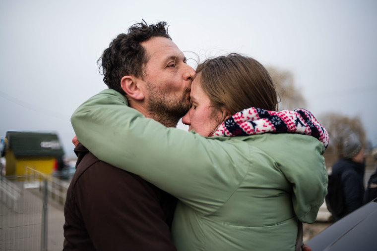 A couple hugs after finding their relatives waiting for them