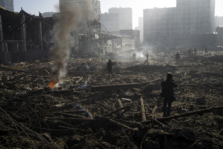 La gente se reúne en medio de la destrucción causada tras el bombardeo de un centro comercial, en Kiev, Ucrania, el lunes 21 de marzo de 2022.