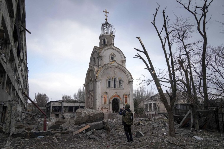 Un militar ucraniano toma una fotografía de una iglesia dañada tras un bombardeo en un barrio residencial de Mariupol, Ucrania, el jueves 10 de marzo de 2022.