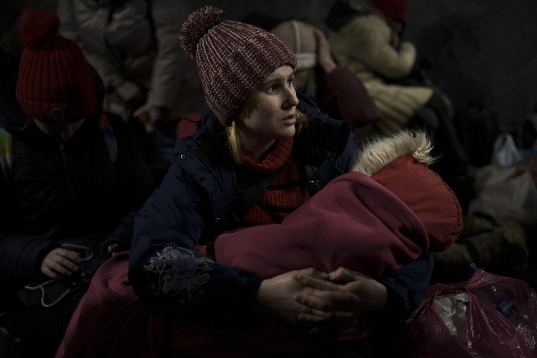 Aleksandra Tytywnnik sostiene a su hija mientras espera un tren en la estación de Lviv para escapar de Ucrania