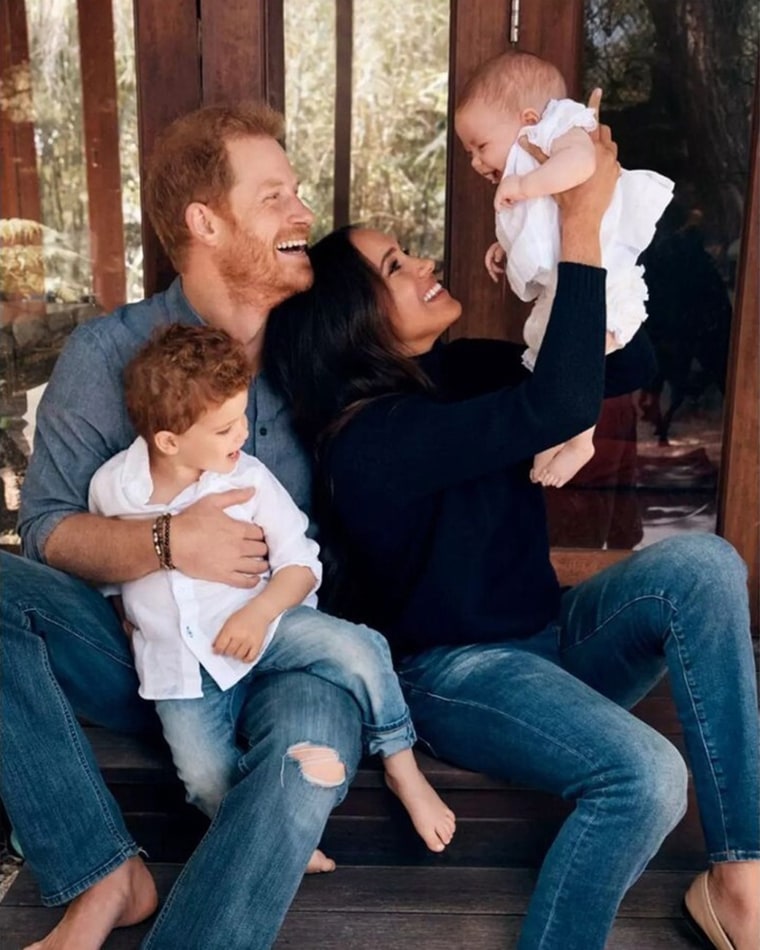 Prince Harry, Duke of Sussex sits with Archie Mountbatten-Windsor in his lap. Next to him is Meghan, Duchess of Sussex with their daughter Lilibet Mountbatten-Windsor.