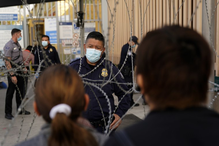 Un funcionario de aduanas de Estados Unidos habla con personas que esperan para cruzar en el Puerto de Entrada de San Ysidro, el lunes 8 de noviembre de 2021, en Tijuana, México.