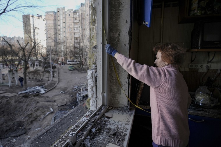 Una mujer examina una ventana en un edificio dañado por un bombardeo en Kiev, Ucrania, el lunes 21 de marzo de 2022.