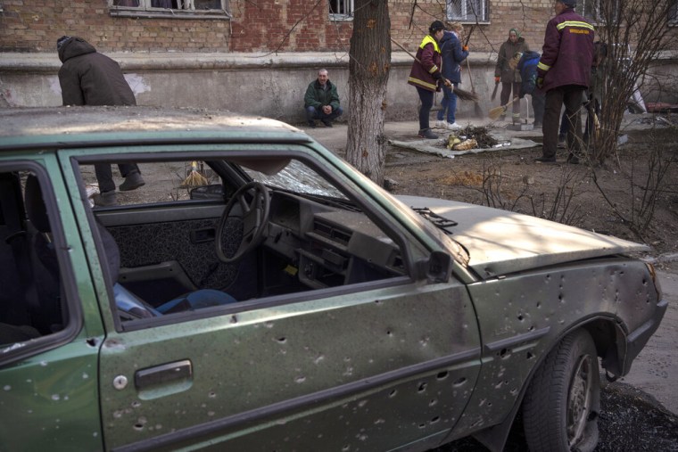 Gente limpia las calles después de que bombardeos dañaran varios apartamentos, en Kiev, Ucrania, el miércoles 23 de marzo de 2022. 