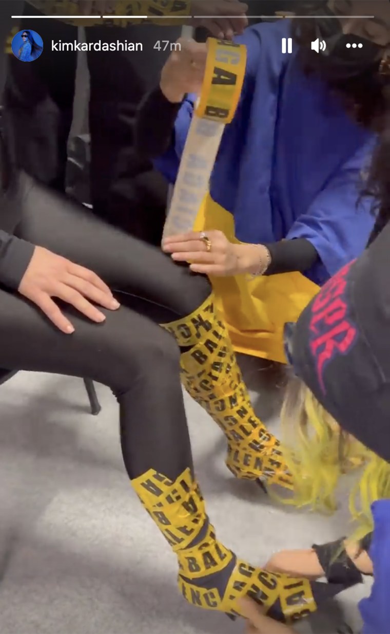 Kim Kardashian getting covered in yellow Balenciaga-themed caution tape. 