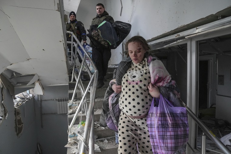 An injured pregnant woman makes her way downstairs in a maternity hospital damaged by shelling in the besieged port city of Mariupol, Ukraine on Wednesday, March 9, 2022. A Russian attack has severely damaged the hospital, Ukrainian officials say. 