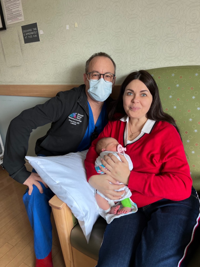 Olesia holds her daughter, Kira, while posing with one of the health care professionals who helped her give birth.