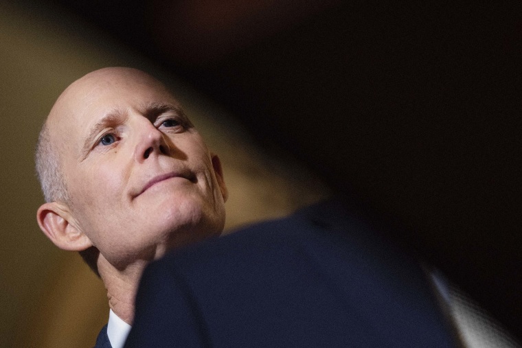Sen. Rick Scott listens as Senate Minority Leader Mitch McConnell speaks to reporters at the U.S. Capitol March 22 in Washington, D.C.