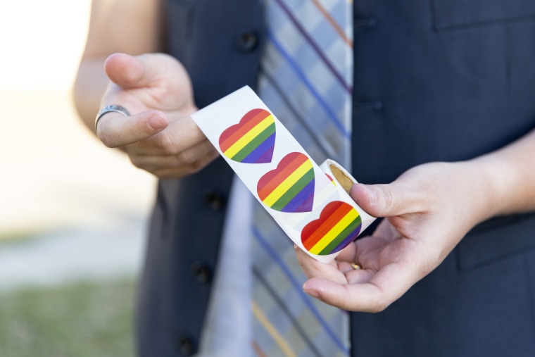 Rachel Stonecipher holds of a roll of rainbow heart stickers like those that teachers placed outside their classrooms at MacArthur High School.