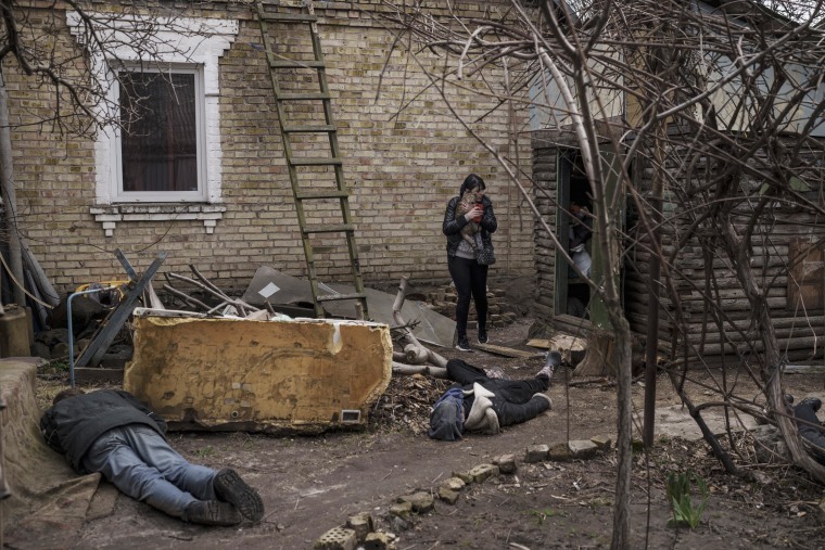 Ira Gavriluk holds her cat as she walks among the bodies of her husband, her brother and another man who were killed outside her home in Bucha.