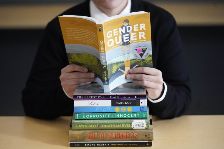 Amanda Darrow holds "Gender Queer: A Memoir" among a stack of books that have been the subjects of complaints from parents in Salt Lake City.