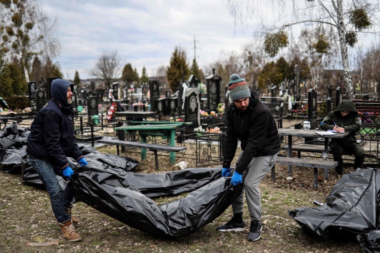Workers line up bodies for identification by forensic personnel at a cemetery in Bucha, Ukraine, on April 6, 2022.