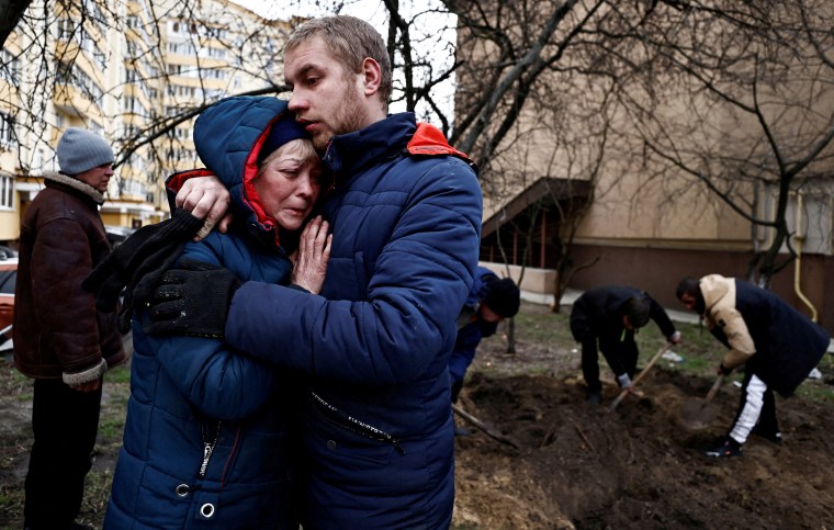 Serhii Lahovskyi hugs Ludmyla Verginska as they mourn their common friend, who according to residents was killed by Russian Soldiers, in Bucha
