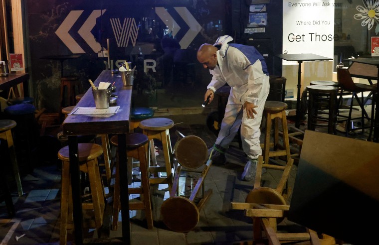 Image: A forensics expert investigates the scene of a shooting in Dizengoff Street in Tel Aviv on April 7, 2022.