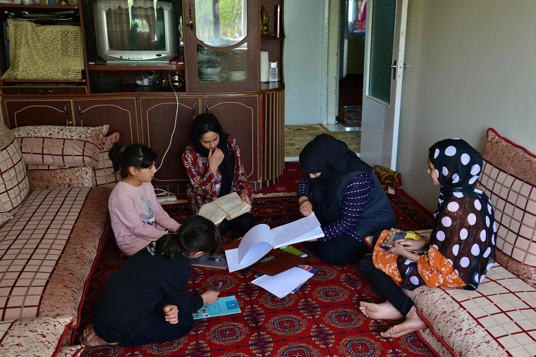 Image: School girls Malahat Haidari, right, and her sister Adeeba Haidari, center, study at their home with their younger sisters and mother in Kabul on March 24, 2022.