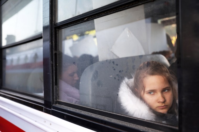 Ukrainians who are seeking asylum sit on a bus