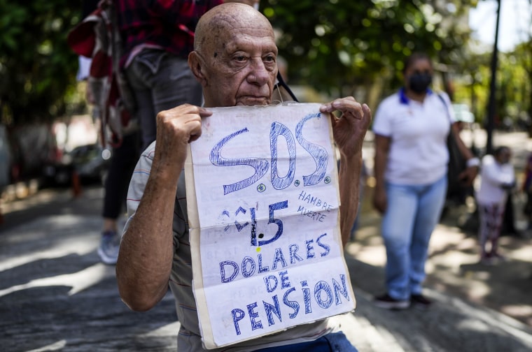 Carlos Blanco, 84, a retired ambulance supervisor, holds a sign that announces his monthly pension payment of $1.50 dollars during a protest asking for an increase in payments amid world record-breaking inflation in Caracas, Venezuela, on Feb. 15, 2022.