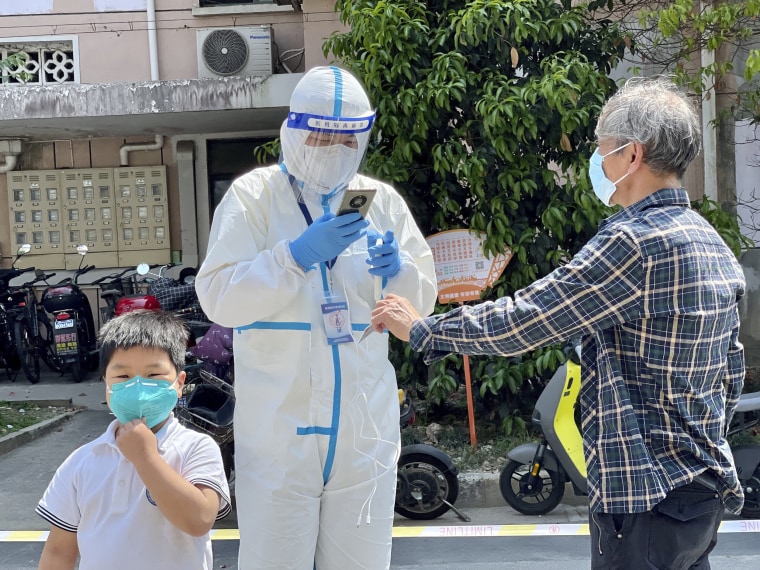 A worker in PPE scans the ID card of a man during Covid-19 screening in a residential block in Shanghai on Wednesday.