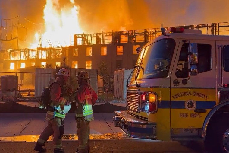 Firefighters near a large structure fire named the Promenade Fire, off Highway 101 in Southern California, Tuesday.