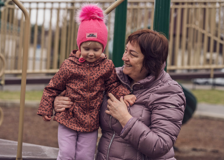 Anna, 2, standing with her grandmother at the playground across the street from her family’s new home in Westfield, Mass., on April 7.