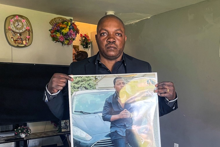 Image: Peter Lyoya holds up a picture of his son Patrick Lyoya, 26, in his home in Lansing, Mich., April 14, 2022.