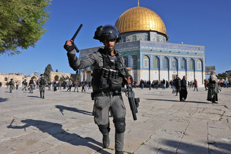 A member of the Israeli security forces lifts his baton in front of the Dome of the Rock mosque during clashes at Jerusalem's Al-Aqsa mosque compound on April 15, 2022.