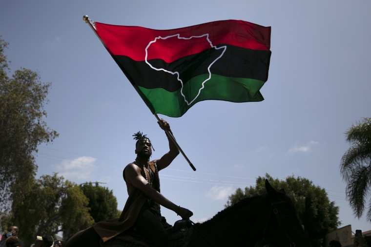 Rein Morton waves a Pan-African flag on horseback during a Juneteenth celebration in Los Angeles on June 19, 2020.