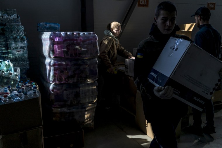 Melaniya Podolyak, a former political aide and now a manager of a warehouse bringing supplies for the Ukrainian military, center, sorts goods to be shipped out on April 13, 2022, in Lviv.
