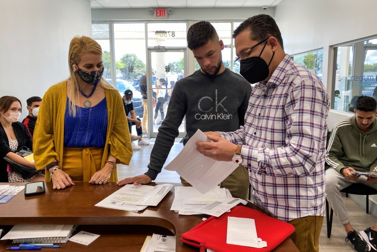 Oasis Pena, left, and Dr. Raul Gonzalez, right, help a migrant at the Integrum Medical Group in Miami on April 18, 2022.