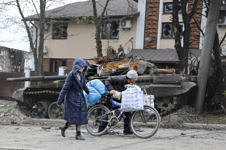 Civilians walk past a tank destroyed during heavy fighting in an area controlled by Russian-backed separatist forces in Mariupol, Ukraine on Tuesday.