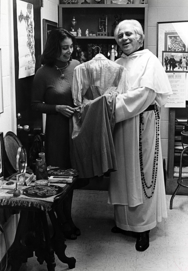 Father Gilbert Hartke holds the dress.