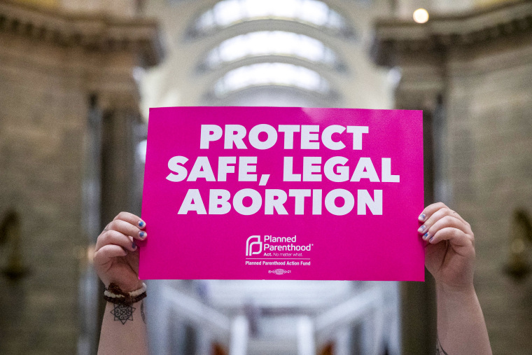 A protester holds a sign at the capitol in Frankfort, Ky., on April 13, 2022.