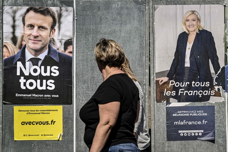 Image: Pedestrians walk past campaign posters of French President and La Republique en Marche (LREM) party candidate for re-election Emmanuel Macron and French far-right party Rassemblement National (RN) presidential candidate Marine Le Pen in Eguisheim, eastern France, on April 21, 2022.