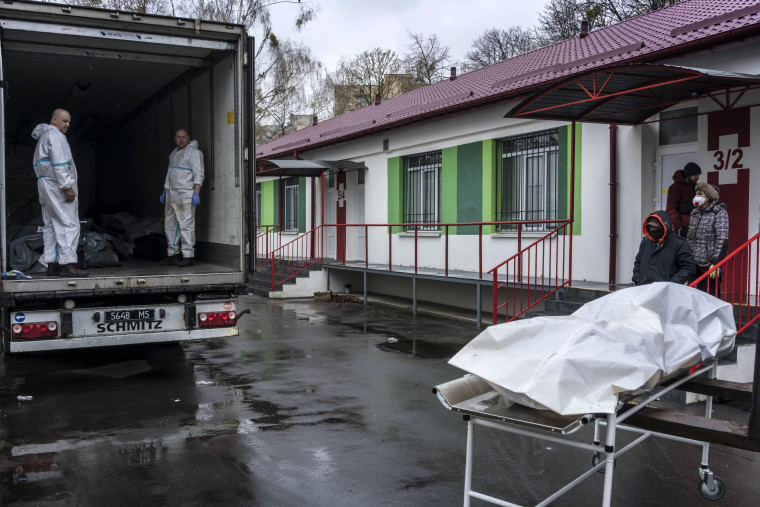 Image: Bodies of civilians are loaded onto a trailer for storage until they can be identified and claimed by family outside the morgue in Bucha on Friday.