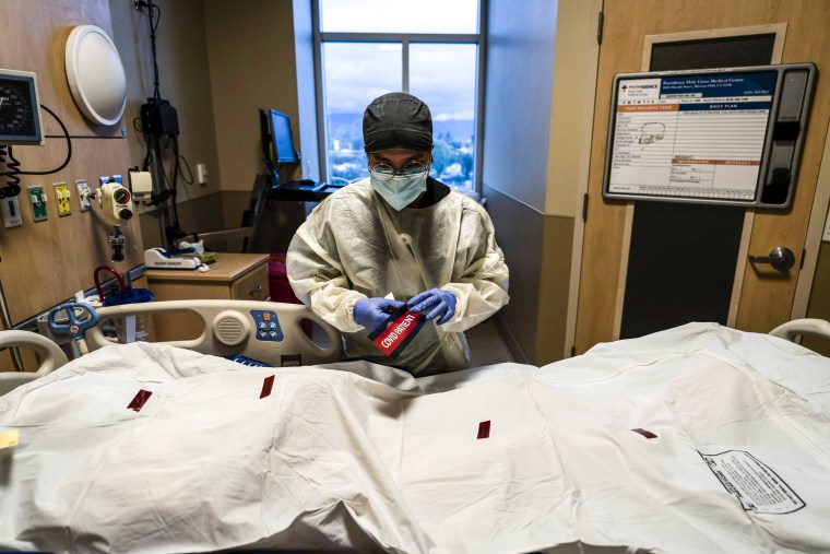 A registered nurse attaches a "COVID PATIENT" sticker on a body bag of a patient who died of coronavirus at Providence Holy Cross Medical Center in Los Angeles on Dec. 14.