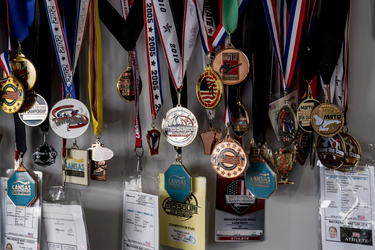 Taekwondo medals belonging to MacKenzie Loesch hang on a wall in her home gym in Marthasville, Mo.