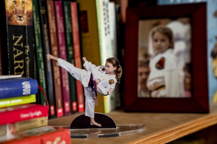 Photos of MacKenzie Loesch as a child are displayed on a bookshelf at her home in Marthasville, Mo.