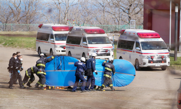 Firefighters transfer a person rescued from a tour boat Sunday in Shari, in the northern island of Hokkaido, Japan.