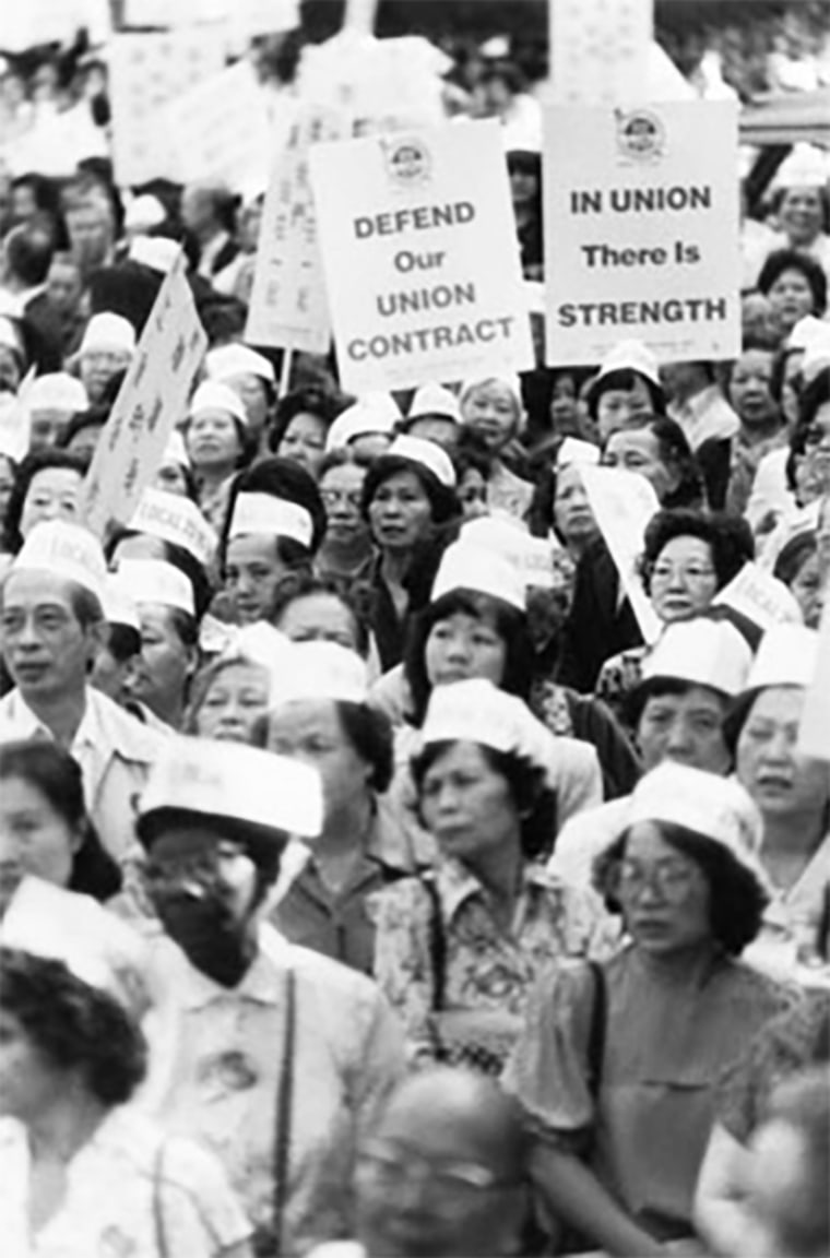 Members of ILGWU Local 23-25 ​​hold placards showing support for the union contract during the Chinatown Rally in New York's Columbus Park.  Rallies took place on June 24, 1982 and July 15, 1982.