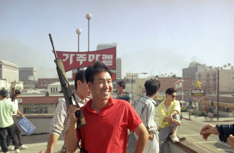 A Korean carries a gun to stop looters from entering a supermarket in Los Angeles on April 30, 1992.