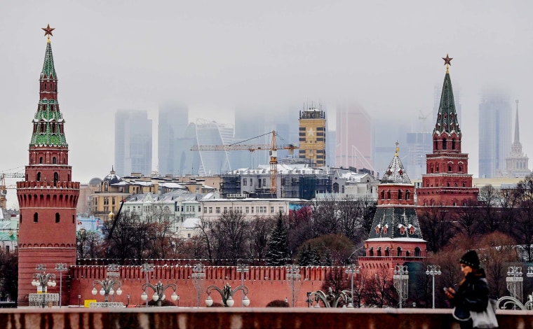 A woman walks in front of the Kremlin and skyscrapers of the Moscow International Business Centre in Moscow on December 17, 2020.