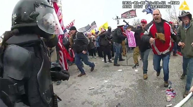 Thomas Webster, in the red, white and black jacket, appears to yell at an officer on Jan. 6, 2021.