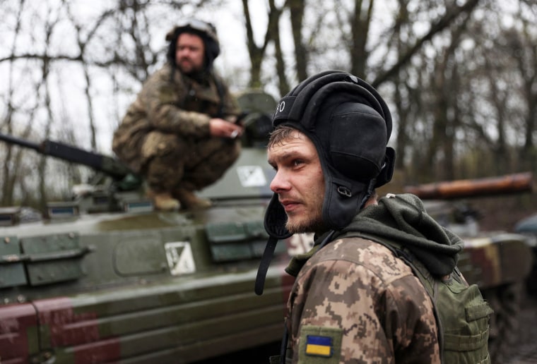 Ukrainian soldiers stand next to their armored personnel carrier