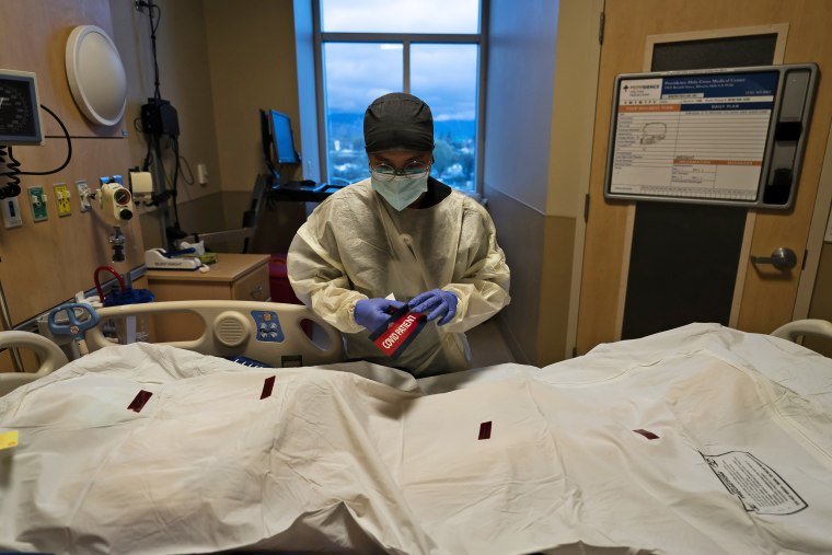 Registered nurse Bryan Hofilena attaches a COVID PATIENT sticker on the body bag of a deceased patient at Providence Holy Cross Medical Center in Los Angeles on Dec. 14, 2021.