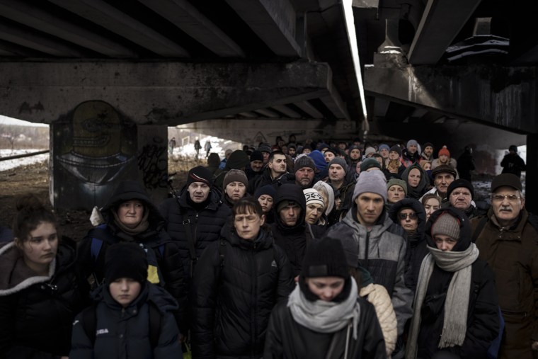 Ukrainians crowd under a destroyed bridge as they try to flee across the Irpin River in the outskirts of Kyiv on March 8, 2022.