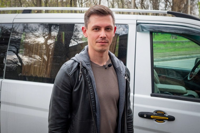 Ballroom dance instructor Nazar Shashkov stands in front of his van, which he used to rescue to his students from his besieged hometown of Mariupol.