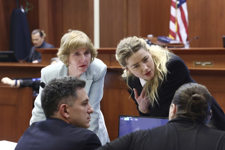 La actriz Amber Heard habla con su equipo legal mientras el actor Johnny Depp regresa al estrado después de un receso para el almuerzo en el Tribunal de Circuito del Condado de Fairfax en Fairfax, Virginia, el jueves 21 de abril de 2022.