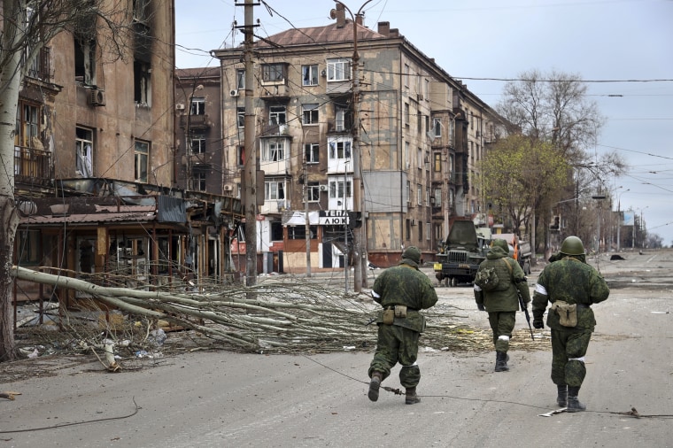 Militares de la milicia de la República Popular de Donetsk caminan entre edificios dañados de apartamentos cerca de la Planta Metalúrgica Ilich de Acero y Hierro, la segunda instalación metalúrgica más grande de Ucrania, en una zona controlada por separatistas con apoyo ruso en Mariupol, Ucrania, el sábado 16 de abril de 2022.