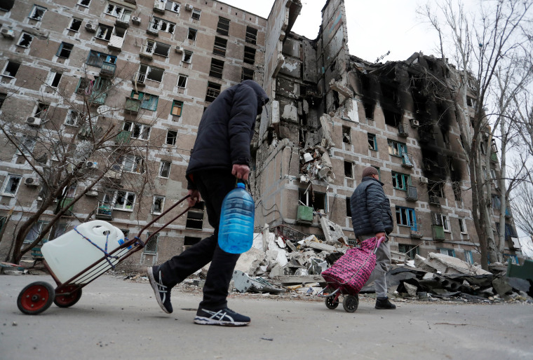 Residentes de Mariupol, Ucrania, pasan por delante de un edificio de apartamentos bombardeado, 4 de abril de 2022.